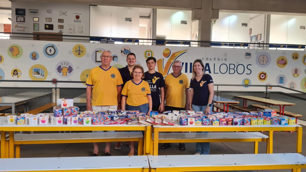 Alunos do Colégio Villa Lobos entregando gelatinas arrecadadas para representantes do Lions Clube de Amparo, destinadas aos hospitais que tratam câncer infantil.